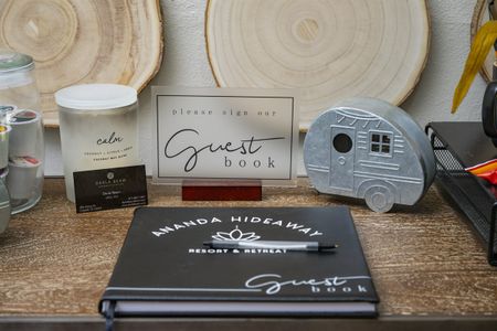 Cozy cabin decor featuring a guest book, candle, and vintage camper, showcasing comfort and local