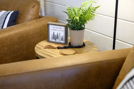 Cozy cabin interior detail showcasing a wooden side table with a decorative fern, framed art