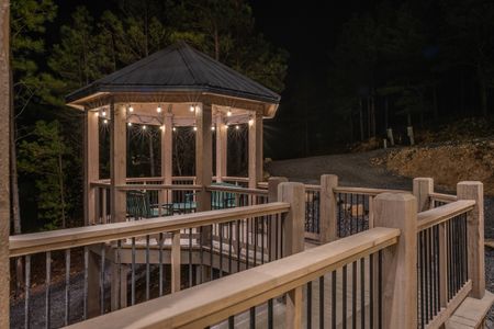 Covered wooden deck with railing and outdoor seating at night