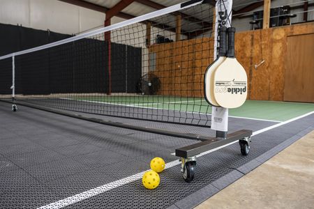 Pickleball paddles and balls arranged on a portable court setup, showcasing a recreational activity