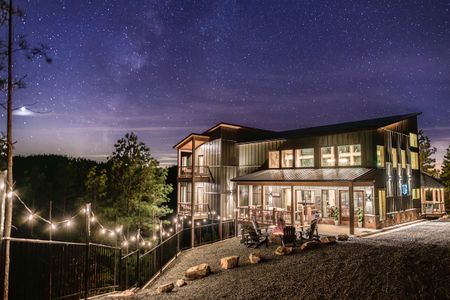Large cabin exterior with illuminated windows and string lights at dusk
