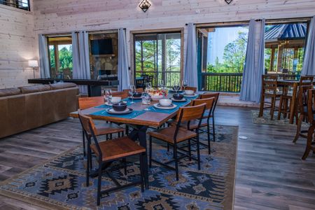 Dining table and wooden chairs in a cabin with green kitchen cabinets