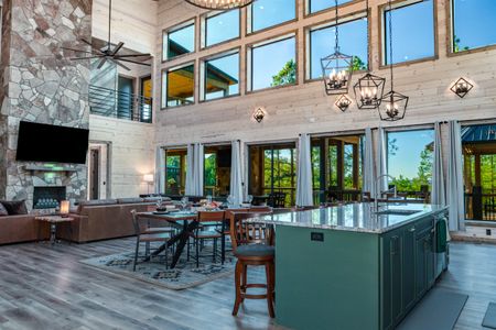 Green kitchen island in an open-plan cabin with a stone fireplace