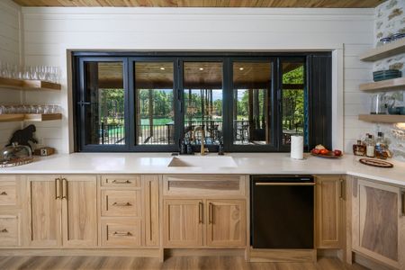 Modern kitchen with wooden cabinetry and a large window showcasing views of the serene outdoor