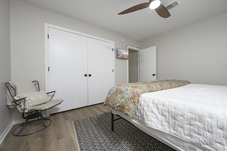 Cozy bedroom interior showcasing a comfortable bed, white arm chair, and built-in closet, reflecting