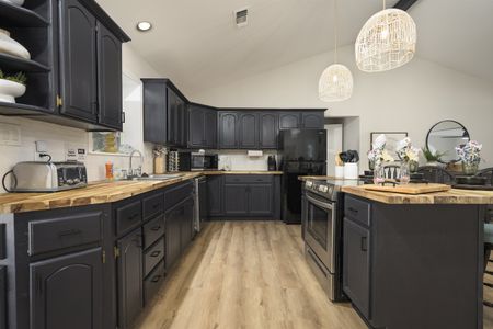 Modern kitchen interior showcasing dark cabinetry, stainless steel appliances, and a light-filled space, offering comfort