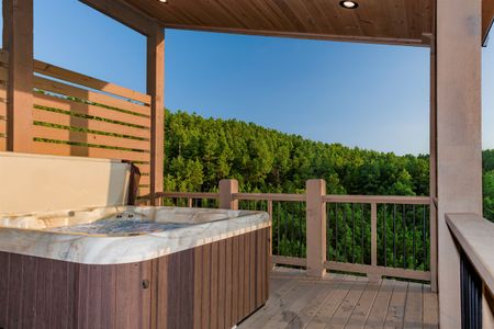Hot tub on a wooden deck overlooking forested hills