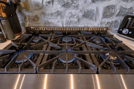 High-end gas stove with multiple burners, set against a rustic stone wall, showcasing the gourmet