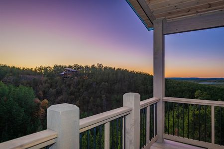 View of forested hills from a covered wooden balcony at sunset
