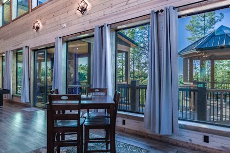 Dining table beside glass doors opening onto a wooded deck