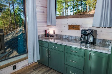 Green kitchen cabinets with a white countertop and wall decorations
