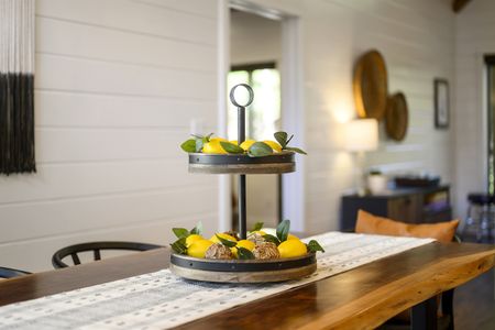 Stylish wooden tiered serving tray with lemons and greenery displayed on a dining table