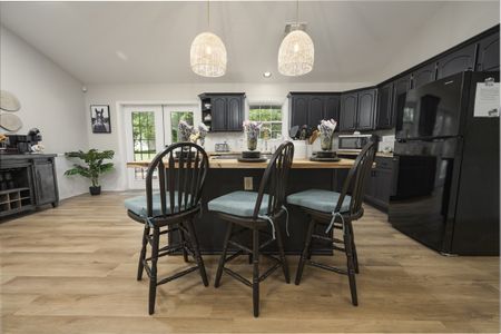 Modern kitchen interior with dark cabinetry, light wood flooring, and seating at a central island