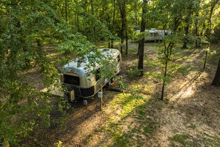 Cozy cabin and modern home rental featuring a vintage Airstream trailer nestled among lush trees