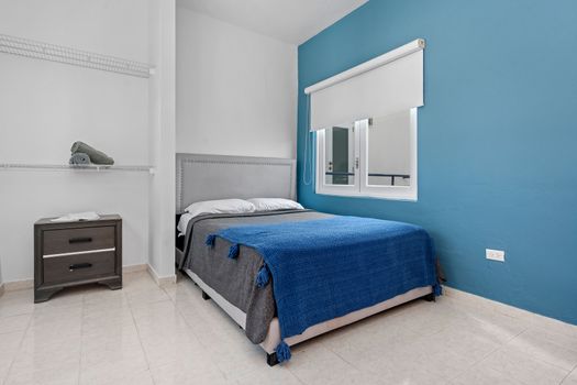 Relax in a peaceful bedroom featuring a comfortable bed paired with a vibrant blue blanket that contrasts beautifully with the calm blue accent wall.