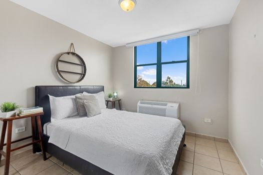 Elegant bedroom with a plush bed, minimalist decor, and a window that frames the sky - your serene retreat after a day of exploration.