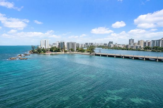Witness the dynamic beauty of Condado from above, where clear waters, distant beaches, and the city skyline converge.