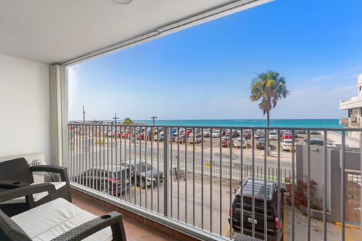 Balcony with direct ocean view, outdoor seating, and panoramic vista of the beach and horizon, ideal for relaxation.