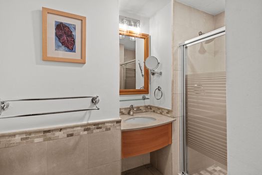 Your pristine bathroom offers a well-lit vanity and a sleek shower design for ultimate comfort.