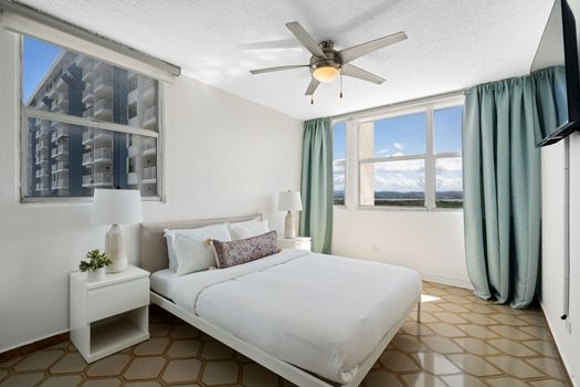 Drift off to sleep in comfort! This serene bedroom features a plush queen-sized bed and expansive windows offering captivating views of the distant mountains and cityscapes.