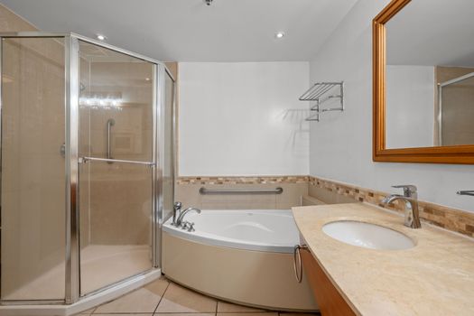 Unwind in the beautifully designed bathroom, featuring a refreshing glass-enclosed shower and a separate, inviting bathtub, perfect for a soothing soak.