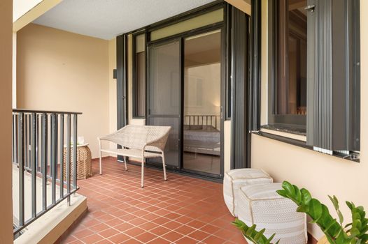 Relax in comfort outdoors! This charming balcony offers a peaceful retreat with views of lush greenery and distant sea.
