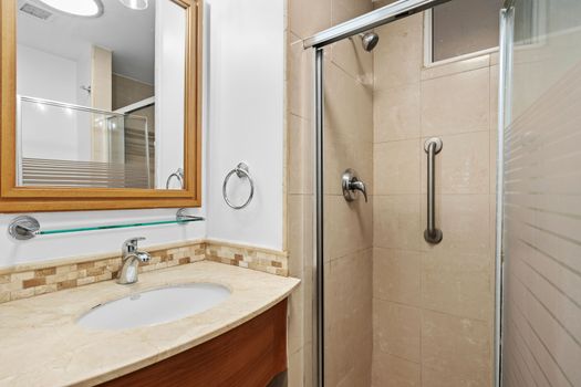 Our bathroom offers a refined experience with a beautiful wooden-framed mirror and a spacious vanity. The bright lighting ensures you have everything you need for your daily routine in a comfortable setting.