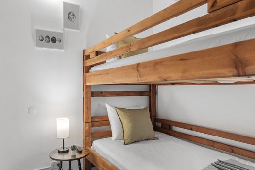Ingrese a un refugio acogedor en nuestra moderna habitación con literas, que cuenta con sábanas blancas limpias y una elegante lámpara de noche.