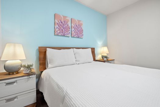 Inviting, pristine queen bed with charming coastal decor for restful nights.