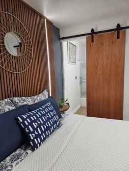 Unwind in a beautifully designed space with warm lighting from the slatted wooden headboard.