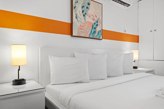 The minimalist decor features a vibrant orange stripe along one wall, adding a pop of color.