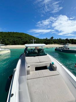 Picturesque harbor views: a classic wooden pier, gleaming boats, and lush green hills under a bright blue sky.