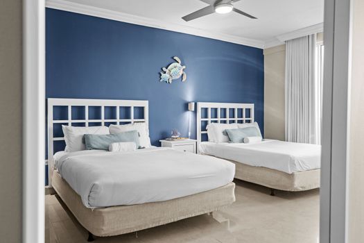 Sleep soundly in this tranquil bedroom featuring two comfortable beds and a ceiling fan for optimal comfort, all while enjoying panoramic water vistas.