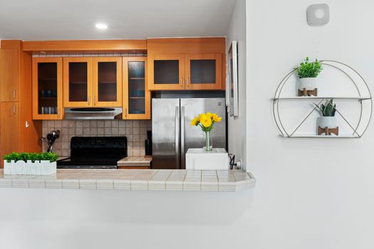 Bright kitchen area with electric stove, microwave hood, and a coffee machine, connecting to a hallway with a blue accent wall.