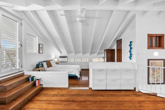 bedroom with bed and private balcony, air condiotioner, wall art and night table and drawers