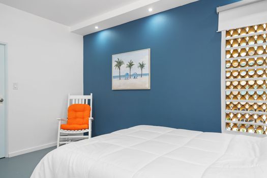 Relax in this well-appointed bedroom featuring a calming blue color scheme, modern artwork, and cozy seating. The room’s contemporary design elements and spacious bed offer a harmonious blend of modern aesthetics and comfort.