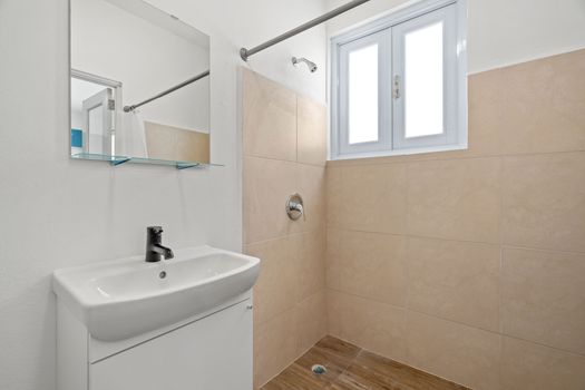 Where cleanliness and simplicity meet, featuring a spacious sink area and a refreshing shower.