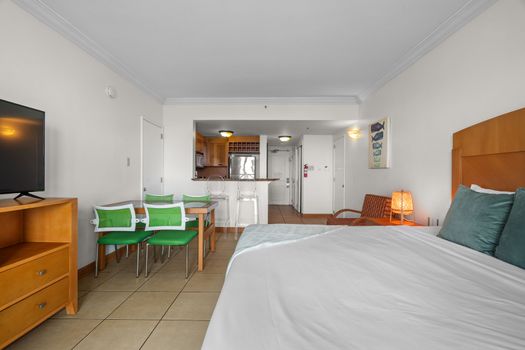 Spacious studio living with a view. This versatile space combines comfortable sleeping quarters, a dedicated dining area, and a cozy armchair – all within sight of the lagoon through the balcony doors.