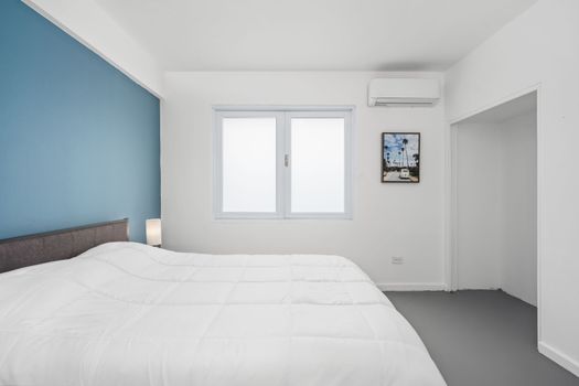 Quede dormido en esta habitación decorada con buen gusto que exhibe una estética moderna realzada por los relajantes tonos de blanco y azul vibrante.