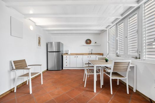 This space features a stylish dining set and a practical kitchenette equipped with a full-sized stainless steel refrigerator and ample counter space.