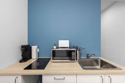 Modern kitchenette with vibrant blue accents and sleek white walls.