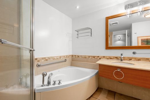 This bright and modern bathroom provides the perfect retreat, with a sleek shower cabin and a comfortable tub, complemented by a stylish vanity and mirror.
