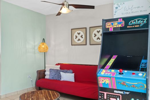 Charming living room with vibrant red sofa, unique decor, and retro gaming for a blend of comfort and fun.