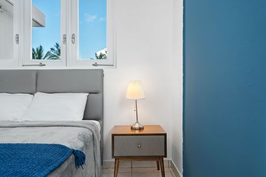 Rest easy in a serene space featuring minimalist design, soft lighting, and a cozy blue blanket that adds a pop of color.
