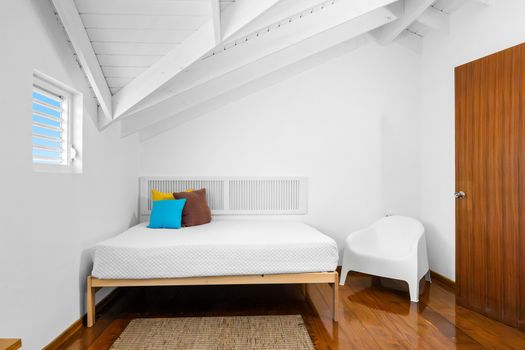 Relax in a bright and airy main room with cozy bed and calming all-white decor – perfect for restful nights.