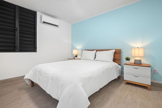 Peaceful bedroom with modern decor and cooling A/C.