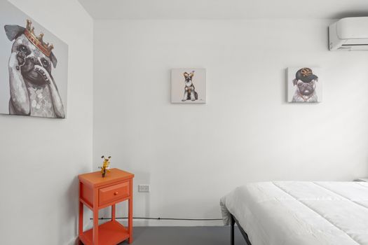 A clean, uncluttered space with a pop of color from an orange nightstand, perfect for a restful stay.