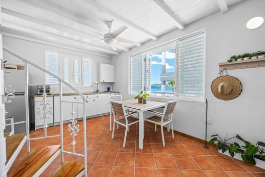 Island-style kitchen with cozy dining space with dining table, ceiling fan