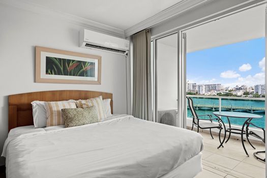 Relax in comfort on your plush, king-sized bed, featuring serene decor and ample light.