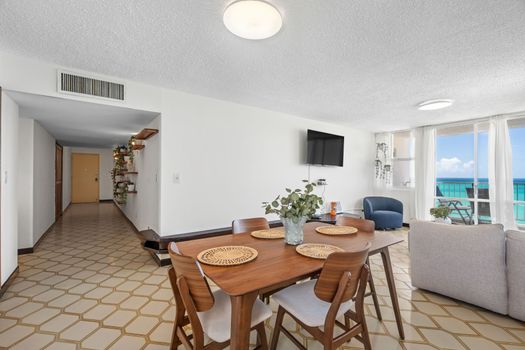 Dine with a view! This open-concept living and dining area provides a perfect space for shared meals, with glimpses of the ocean adding to the inviting ambiance.